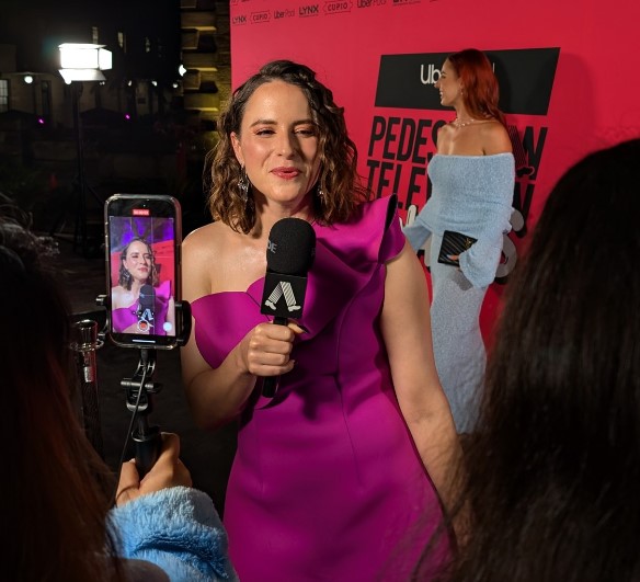 a woman in a purple dress is talking into a microphone