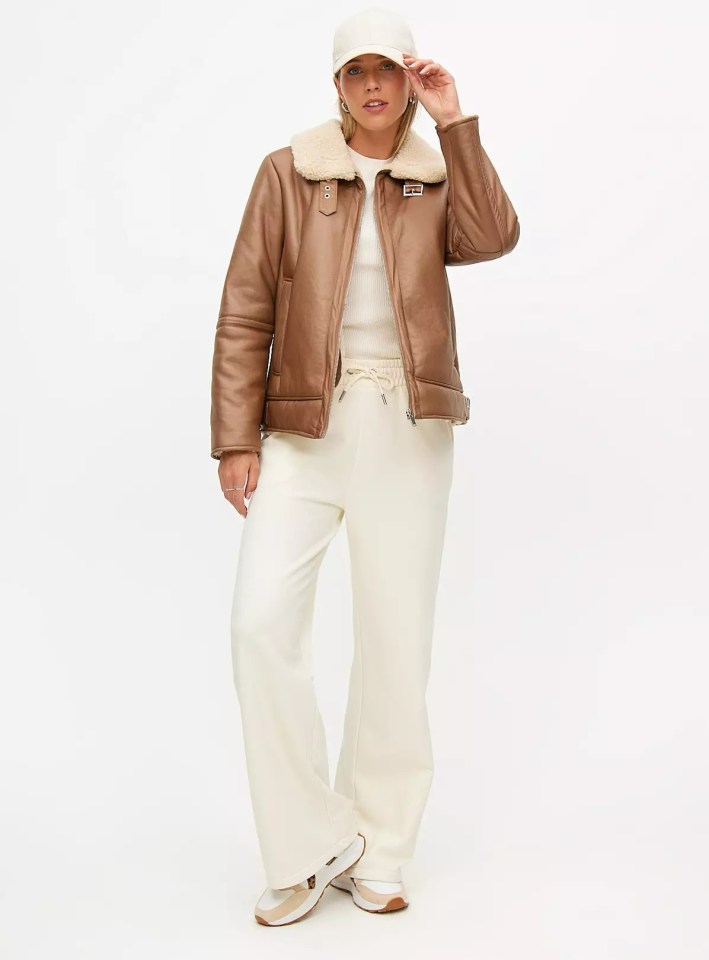 a woman wearing a brown jacket and white sweatpants