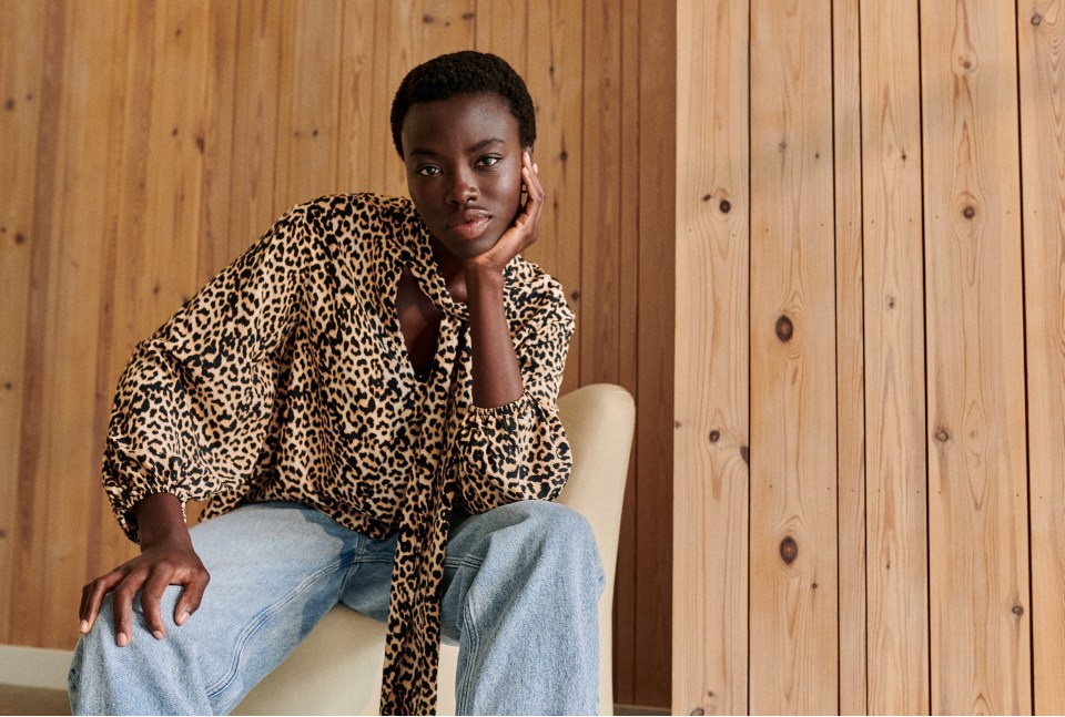 a woman in a leopard print shirt sits on a chair