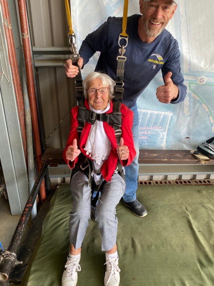 a man giving a thumbs up next to an older woman wearing a parachute harness