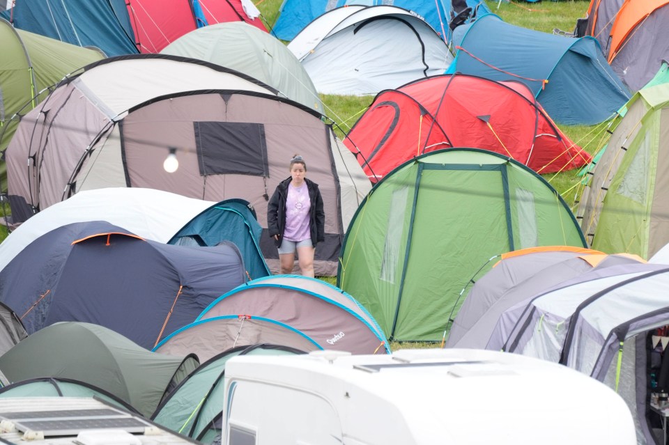 a woman stands in front of a row of tents one of which says quechua