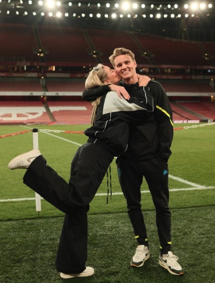 a woman kisses a man on the cheek on a soccer field