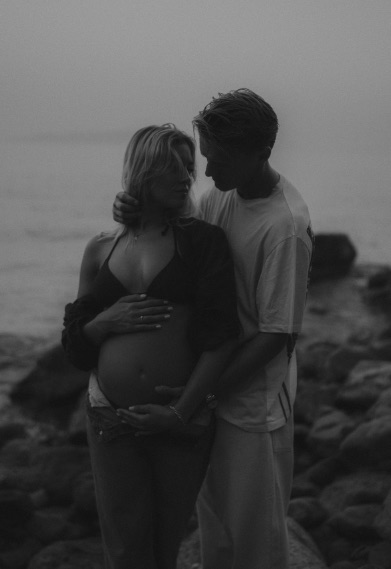 a black and white photo of a pregnant woman and a man