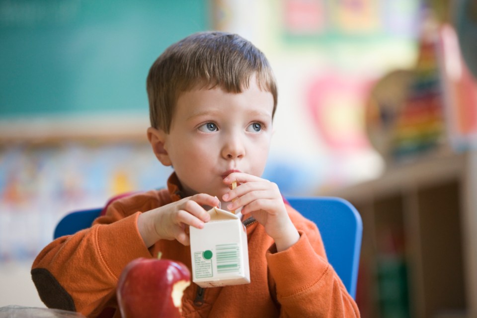 a young boy is drinking from a carton of milk