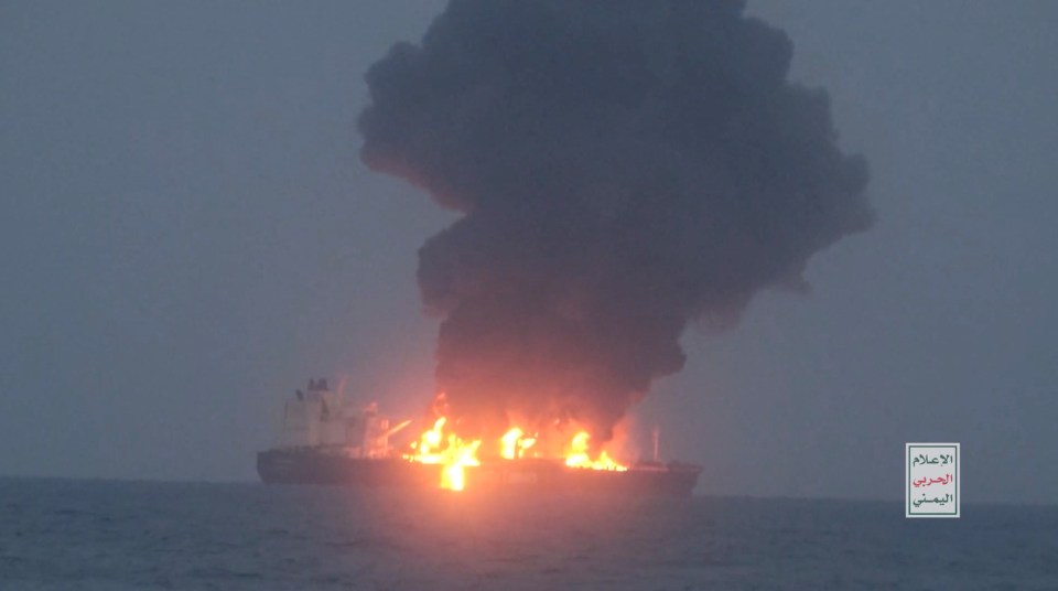 The ship continues to burn as smoke rises