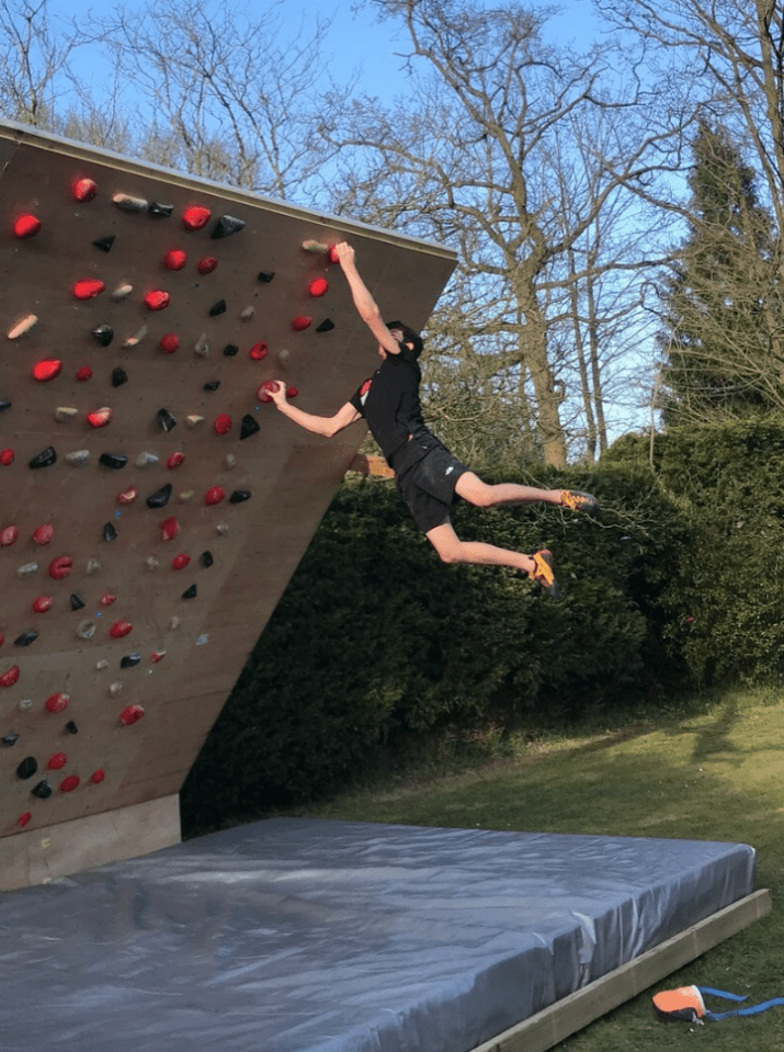 a man is climbing a climbing wall in a backyard