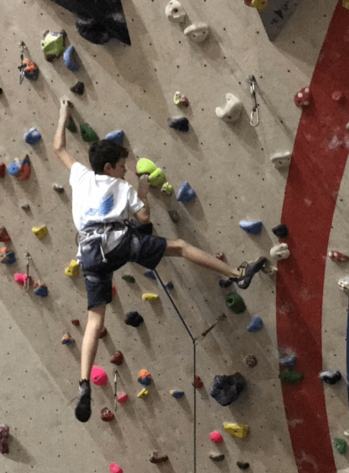 a young boy is climbing a climbing wall