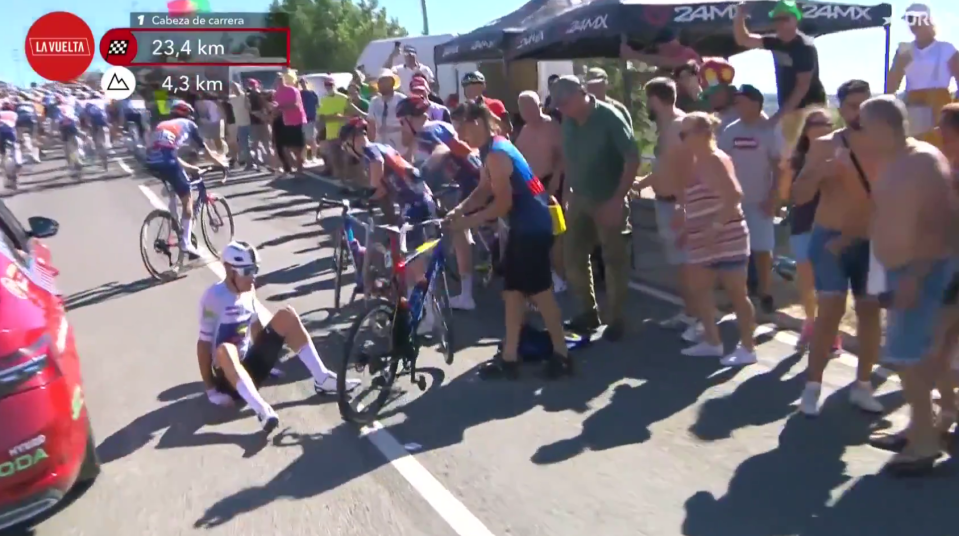 a group of people are gathered on the side of a road with a sign that says la vuelta