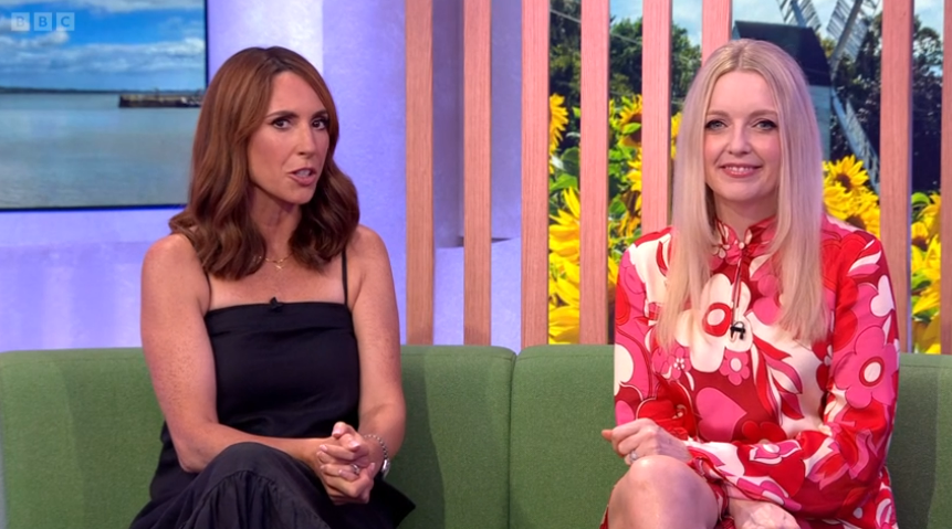 two women sit on a green couch with bbc written on the wall behind them