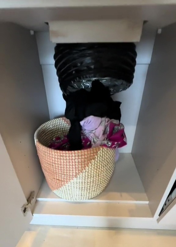 a wicker basket filled with clothes sits in a cabinet