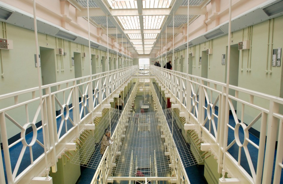 a very long hallway in a prison with a white railing