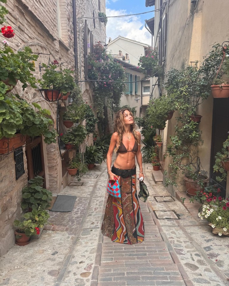 a woman in a bikini is walking down a narrow street