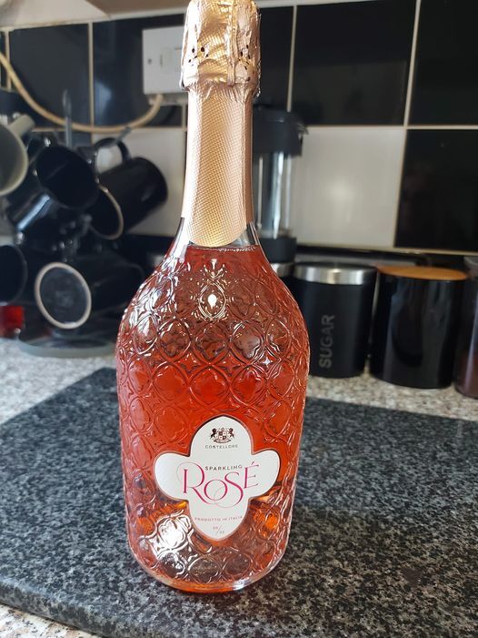 a bottle of rose sparkling wine sits on a counter