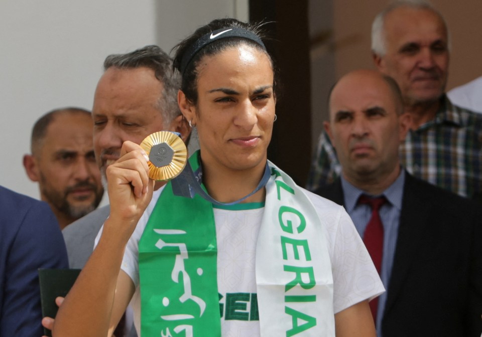 a woman wearing a algeria scarf holds up a medal