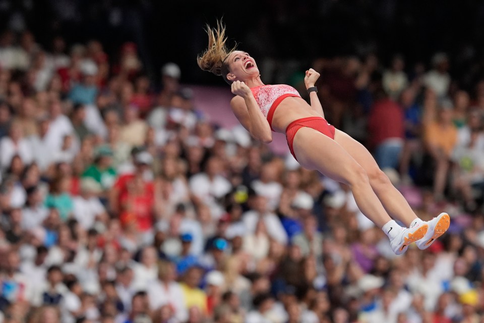 a female athlete is jumping in the air with her arms in the air