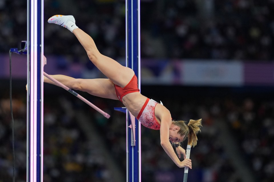 a female athlete is doing a trick on a pole