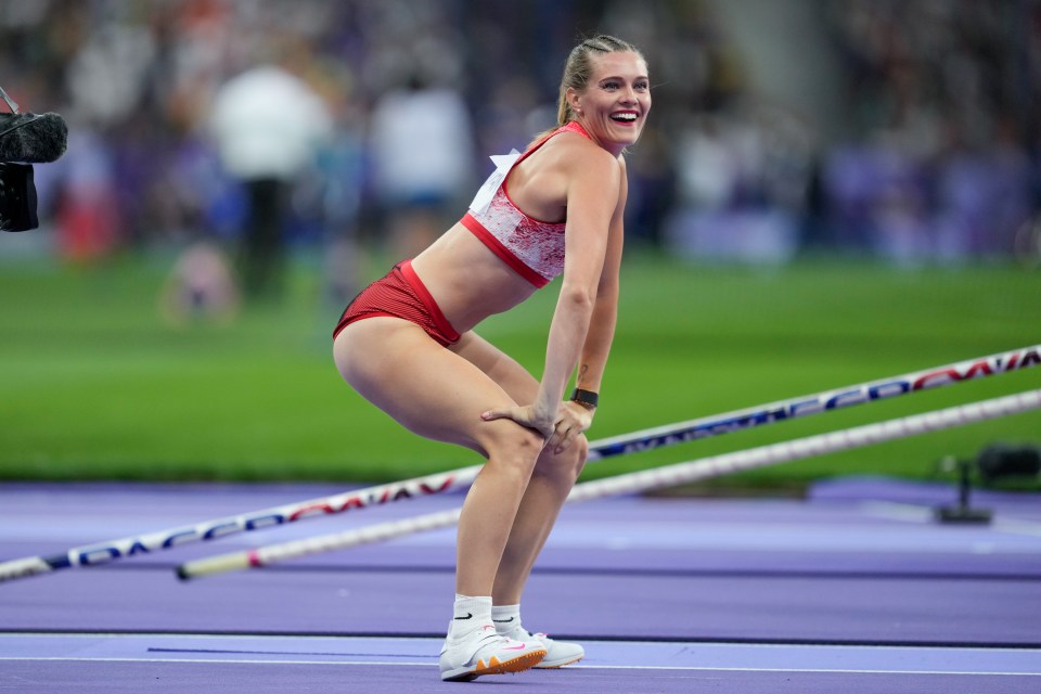 a woman in a red top and red shorts stands on a track