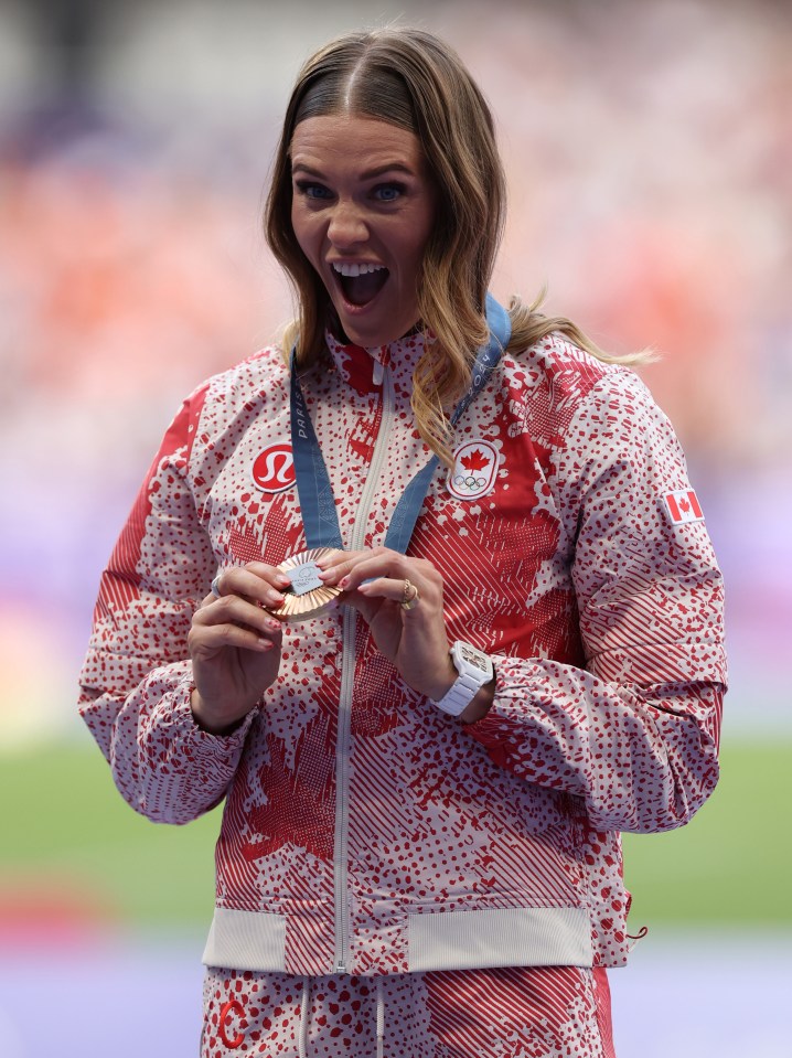 a woman in a red and white jacket is holding a medal