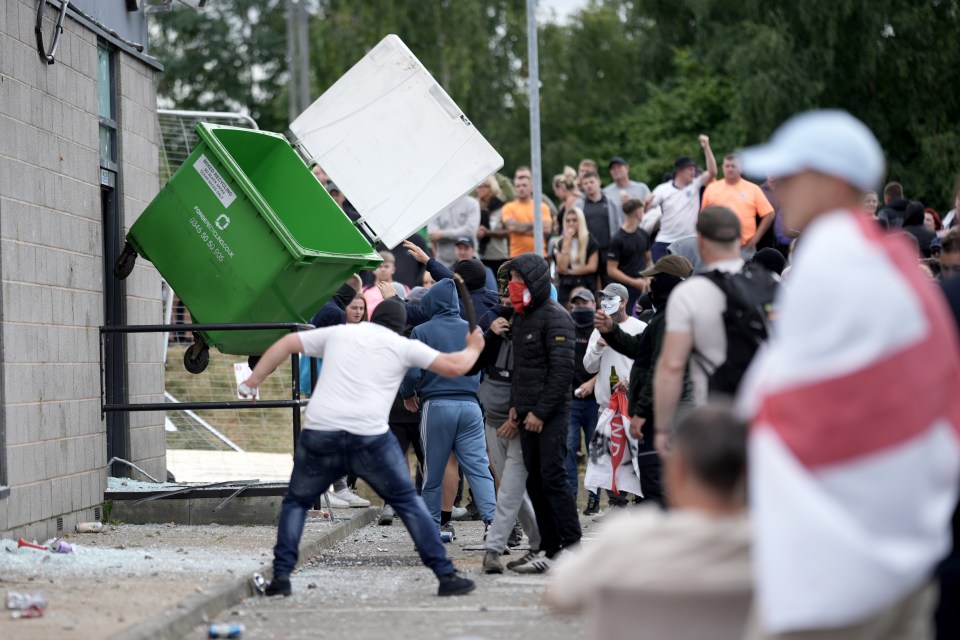 Rioters throw a wheelie bin at the wall of the Holiday Inn Express in Rotherham