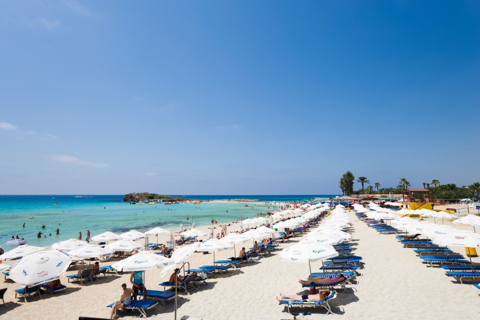 a beach with lots of white umbrellas that say aquafina