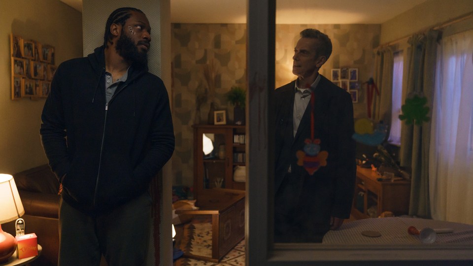 two men are standing in a living room looking out a window