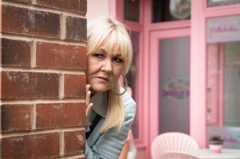 a woman peeking out from behind a brick wall