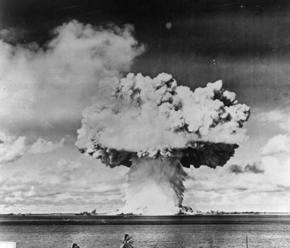 a black and white photo of a mushroom cloud over a body of water