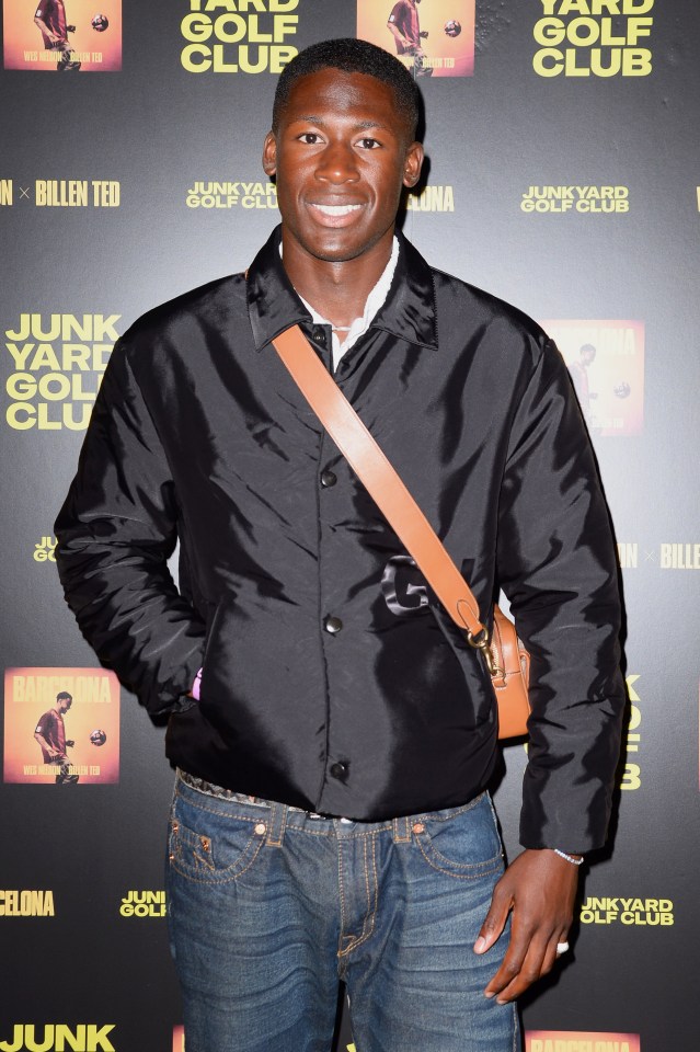 a man stands in front of a poster for junkyard golf club