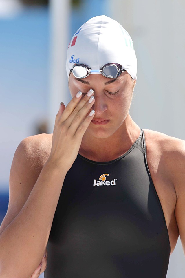 a woman wearing a black jaked swim suit wipes her eyes