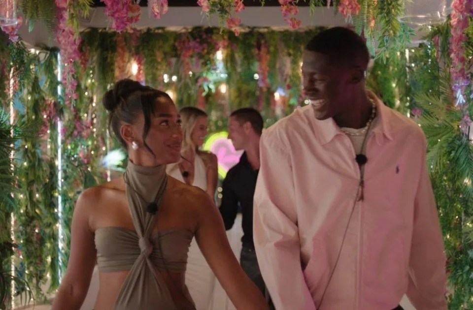 a man and a woman are holding hands in a room with flowers hanging from the ceiling