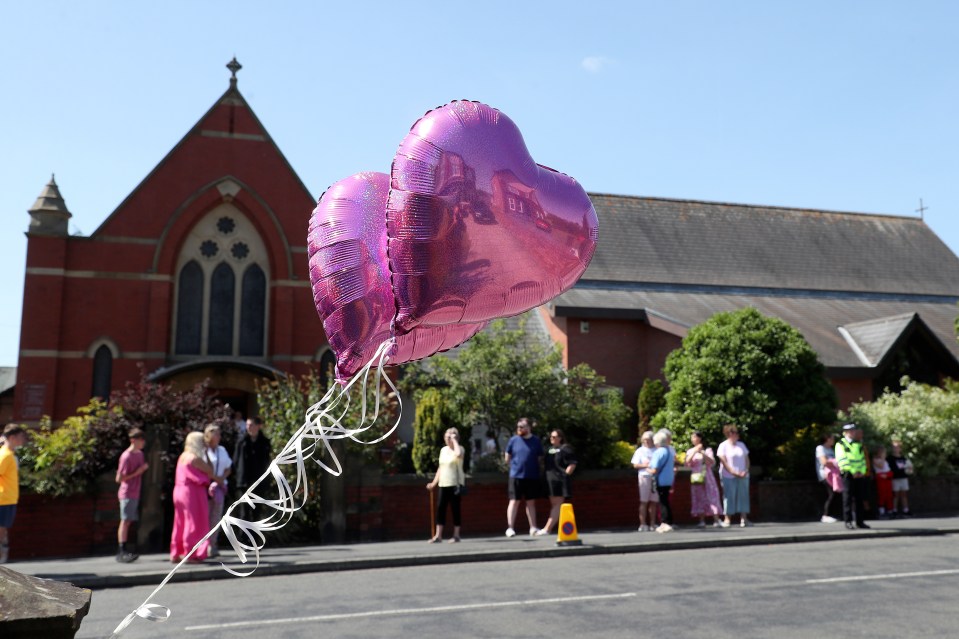 a couple of pink heart shaped balloons hanging from a string