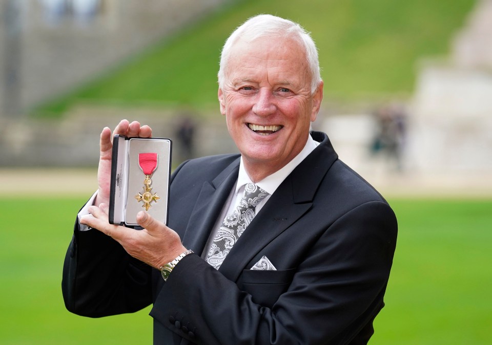 a man in a suit is holding a medal in his hand