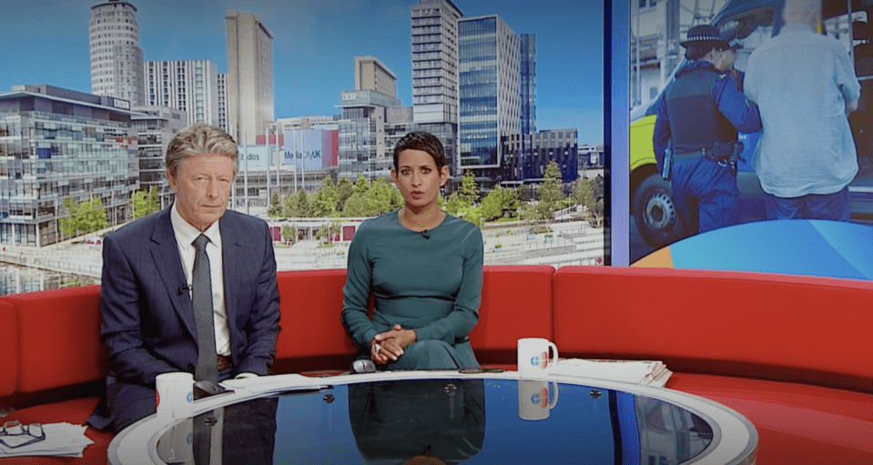 a man and a woman sit on a red couch in front of a city skyline