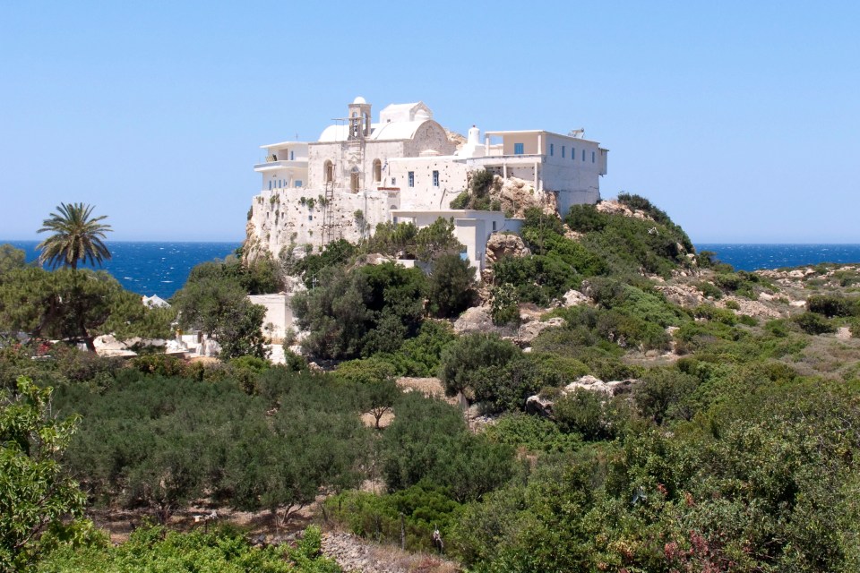 a large white building sits on top of a hill overlooking the ocean