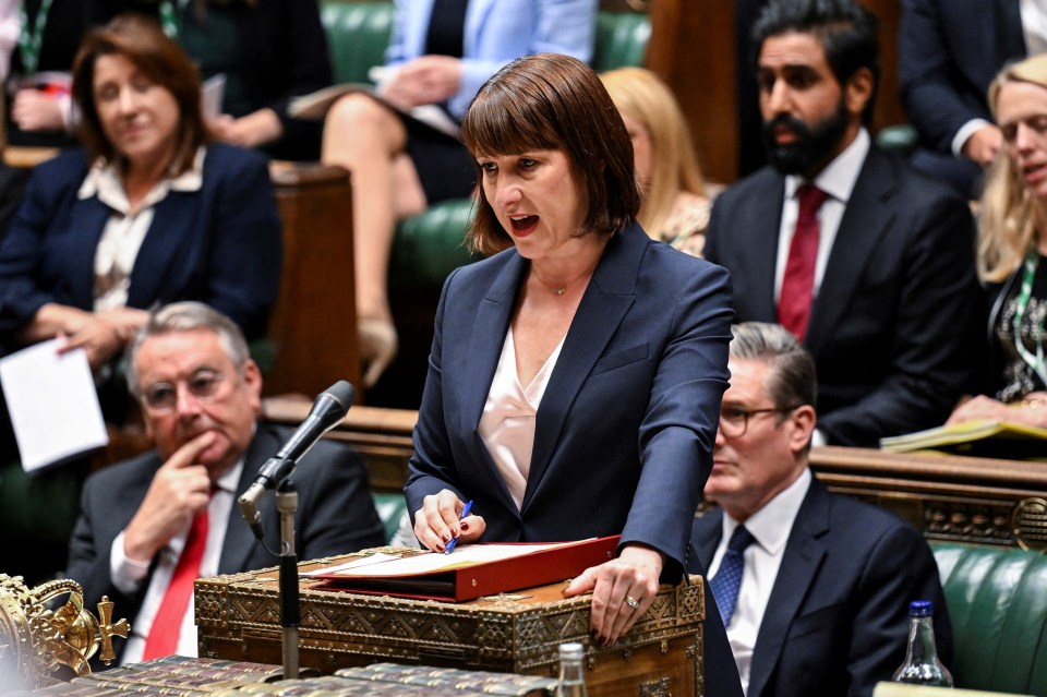 a woman stands at a podium with a red folder in her hand