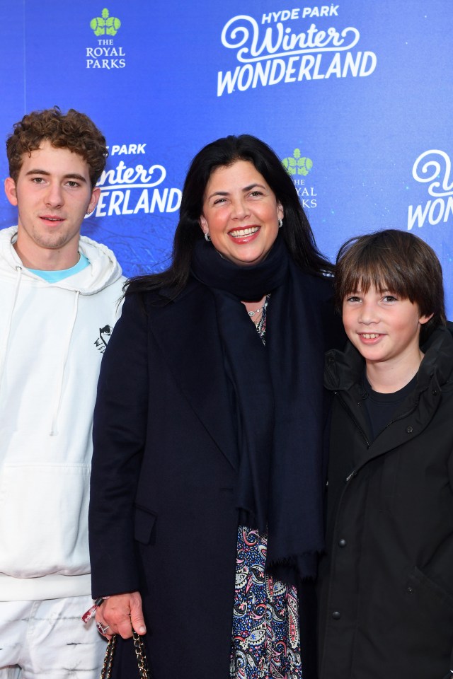 a woman and two boys pose in front of a hyde park winter wonderland sign