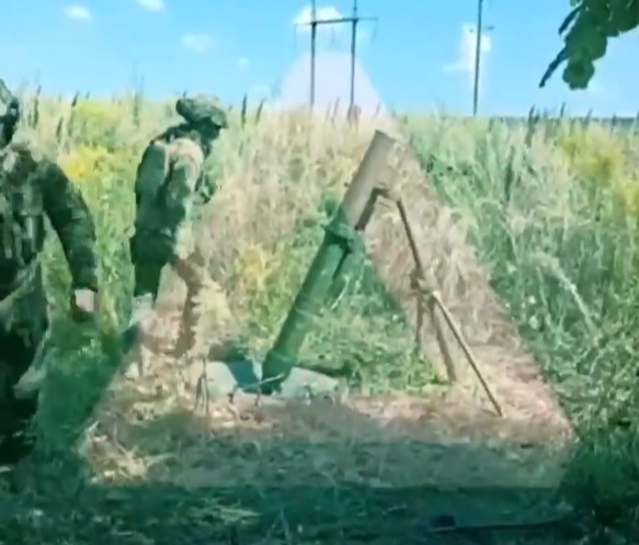 a group of soldiers are standing in a field next to a mortar .