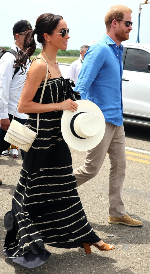 a woman in a black and white striped dress is walking with a man in a blue shirt