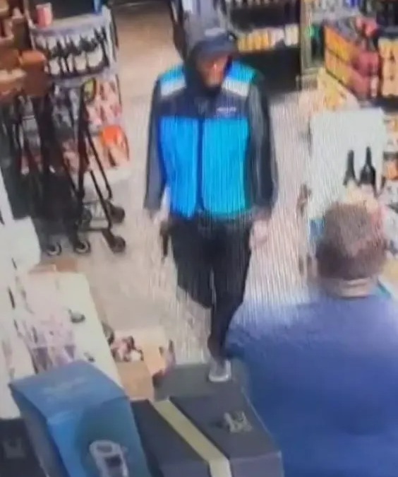 The armed robber makes his way behind the counter