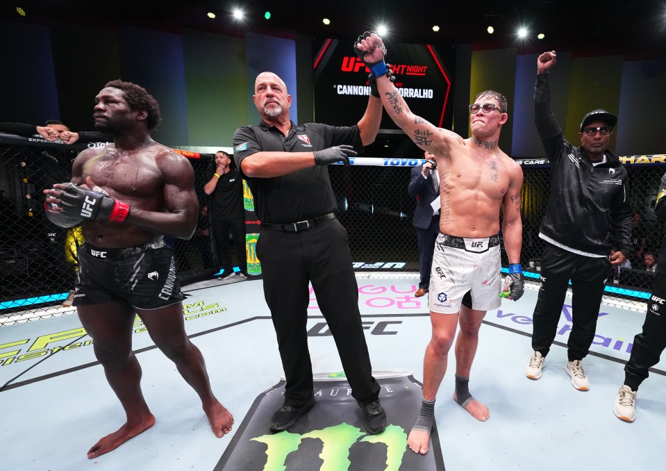 a referee holds up a fighter 's hand in front of a screen that says ufc fight night