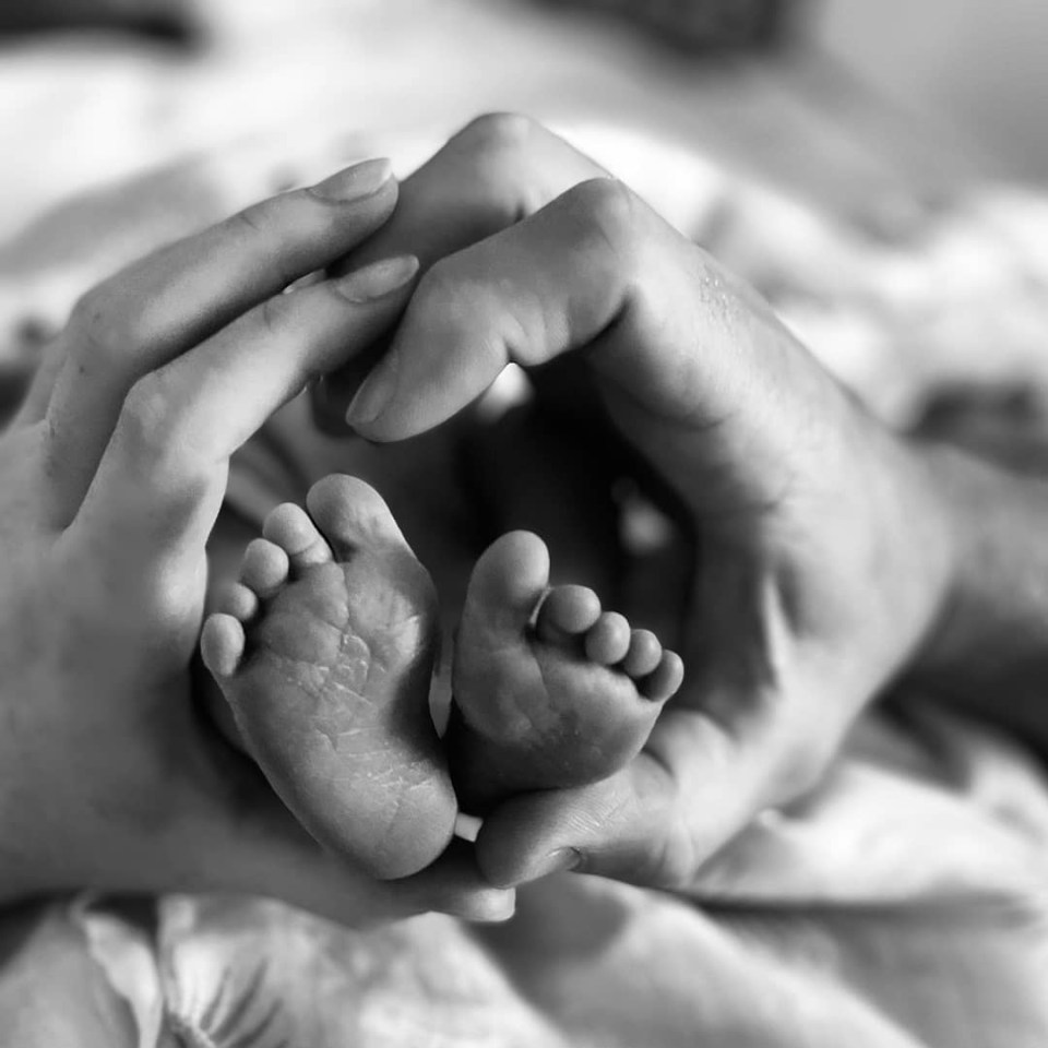 a black and white photo of a person holding a baby 's foot