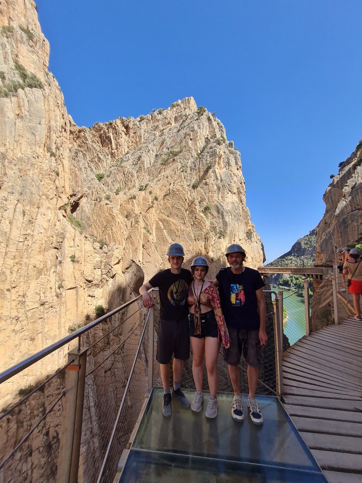 three people standing on a bridge with one wearing a t-shirt that says ' hawaii ' on it