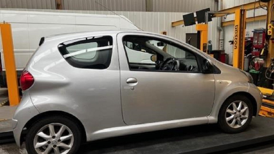 a silver car is sitting on a lift in a garage .