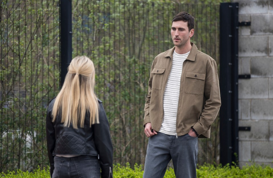 a man and a woman are standing in front of a fence