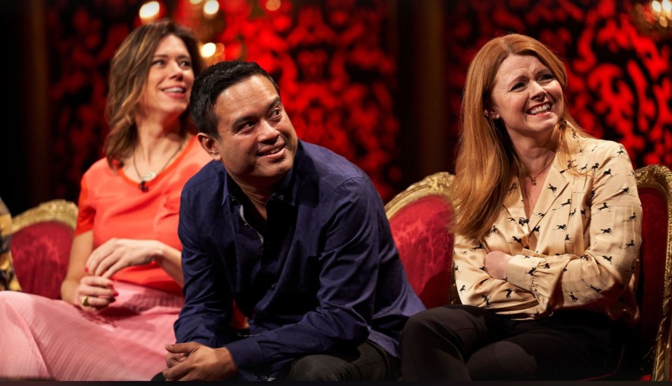 a man and two women sit on a red chair