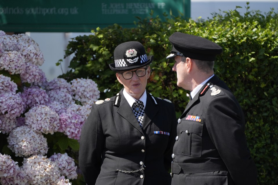 two police officers talking in front of a sign that says john henderson