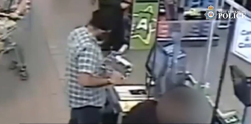 a man in a plaid shirt is standing in front of a counter in a store .