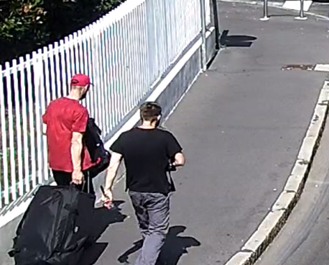 two men are walking down a sidewalk with luggage