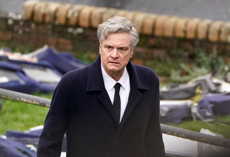 a man in a suit and tie stands in front of a wall