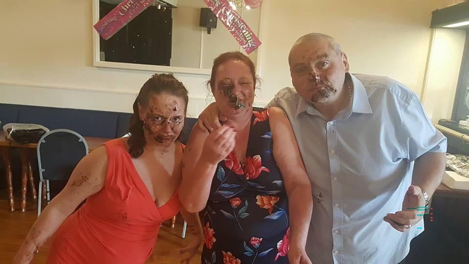 a man and two women are posing for a picture with their faces covered in cake